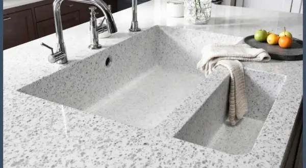 Évier double en quartz ou granit moucheté, avec robinetterie chromée et torchon plié.