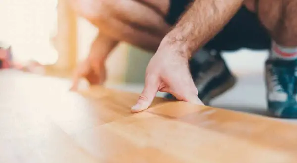 Pose d'une sous couche parquet sur carrelage. Un homme pose délicatement une fine couche isolante avant la pose du parquet.