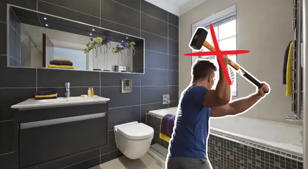Un homme s'apprête à démolir une salle de bain moderne avec une masse. Une croix rouge indique que cette méthode n'est pas recommandée pour la renovation carrelage.
