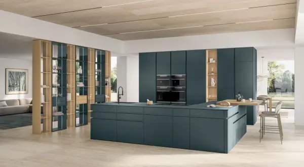 Un sol de cuisine tendance en travertin clair, réchauffant cet espace moderne aux meubles bleu pétrole.