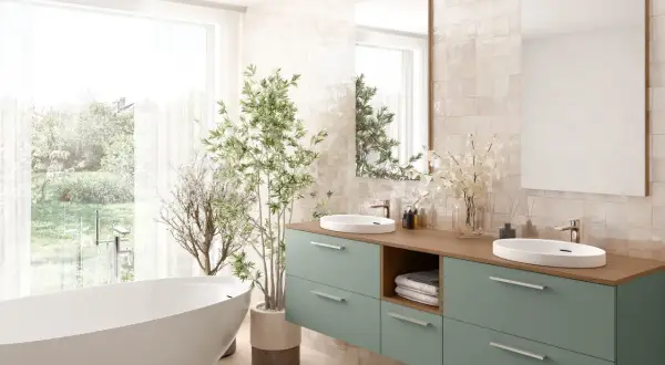 Élégante salle de bain verte et beige avec baignoire îlot, double vasque et plantes luxuriantes.