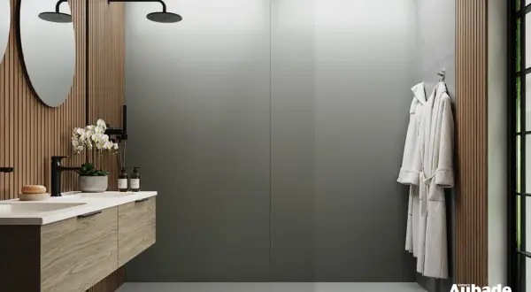 Salle de bain moderne avec lavabo en bois, douches et peignoirs. Le receveur de douche, discret, s'intègre parfaitement.