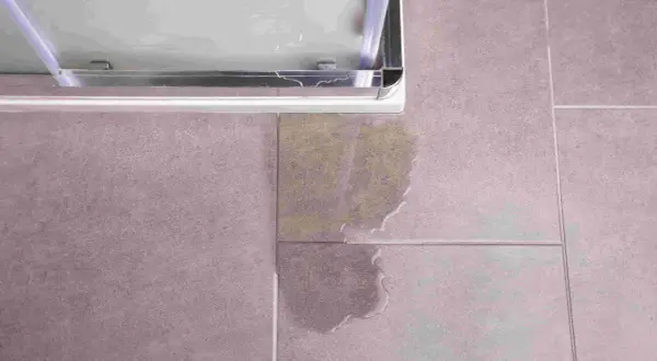 Une fuite sous le bac à douche, une situation qui peut nécessiter une intervention d'assurance. L'eau s'est répandue sur le carrelage.