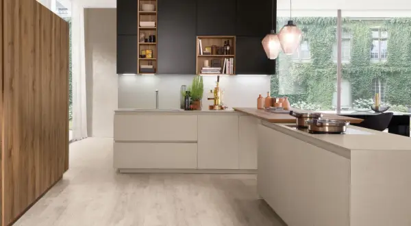 Une cuisine moderne avec des armoires noires et beiges, un îlot en bois et une grande fenêtre donnant sur un mur végétal. Une belle cuisine inspiration pour votre intérieur.
