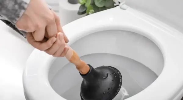 Main tenant utilise une ventouse pour comment deboucher wc.