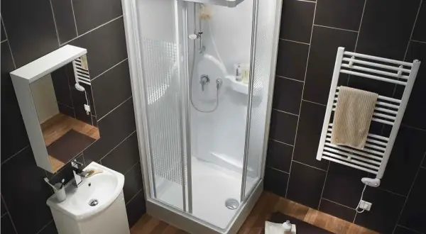 Salle de bain moderne avec une cabine de douche aux dimensions compactes, un lavabo suspendu et un sèche-serviettes.