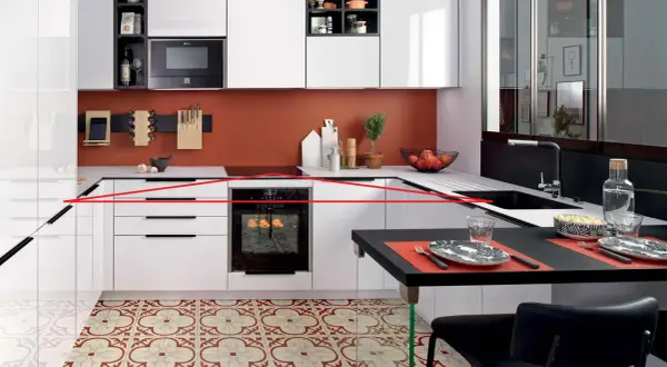 Cuisine moderne avec une organisation optimisée : tiroirs blancs, four encastré, crédence orange, et un îlot noir pour les repas.