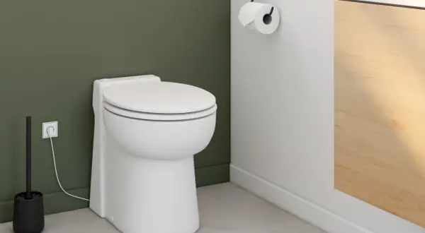 Toilettes modernes avec brosse et prise électrique. Le wc broyeur, discret, est prêt à fonctionner.