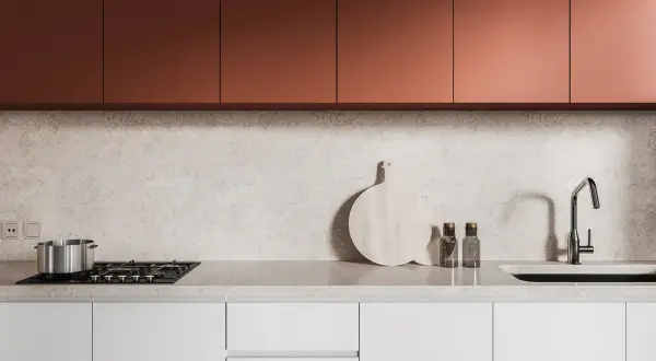 Crédence derrière plaque de cuisson gaz, avec un plan de travail en marbre clair, des placards cuivrés et un évier moderne.