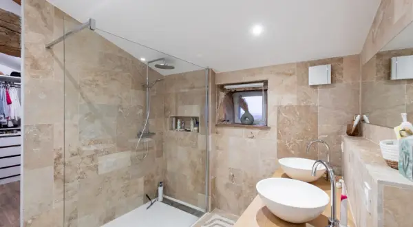 Salle de bain moderne avec douche vitrée, double vasque et dressing. Une rénovation qui pourrait permettre de déduire des impôts des travaux de salle de bain.