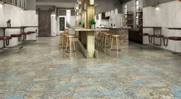 Sol usé et texturé, évoquant le recyclage carrelage, dans un bar industriel avec des tabourets en bois et des banquettes en cuir.