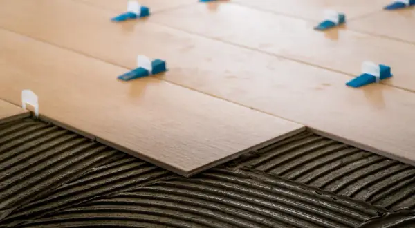 Pose d'un carrelage 60x120 pose décalée, avec des croisillons bleus et blancs assurant un espacement parfait pour un rendu impeccable.
