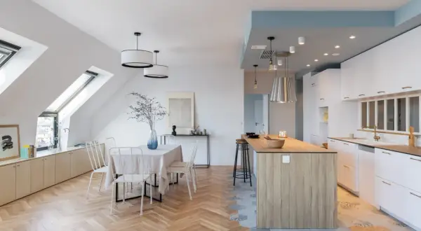Un espace de vie lumineux avec carrelage cuisine ouverte et parquet salon en chevrons. Une table à manger est dressée, prête pour un repas convivial.