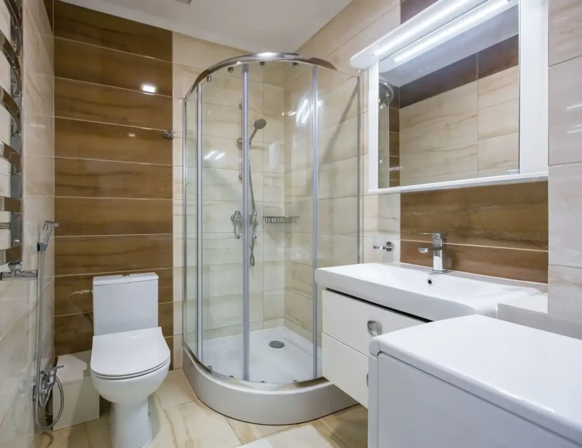 Salle de bain moderne avec douche à l'italienne, lavabo, WC et un banc intégré dans la douche pour plus de confort.