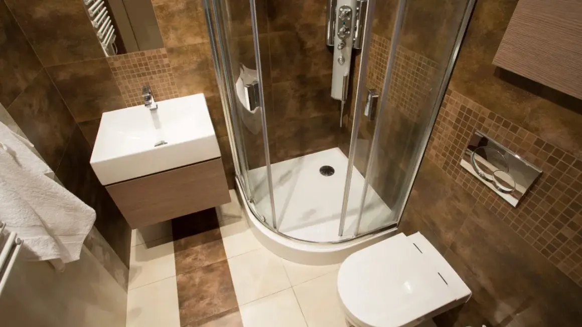 Salle de bain rouille et bois : douche d'angle, lavabo suspendu, toilettes. Ambiance chaleureuse et moderne.