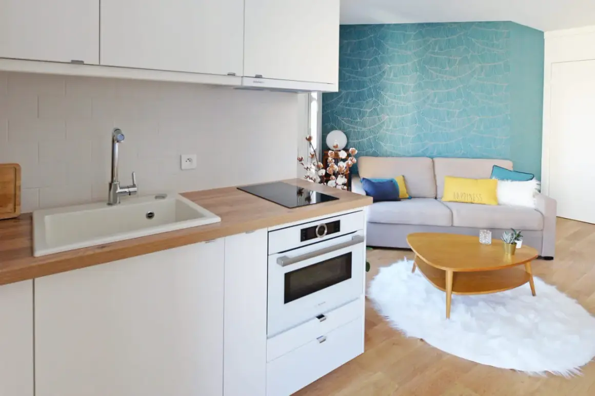 Plan d'une petite cuisine en U moderne avec évier, plaque de cuisson, four et un salon cosy avec canapé bleu et jaune.