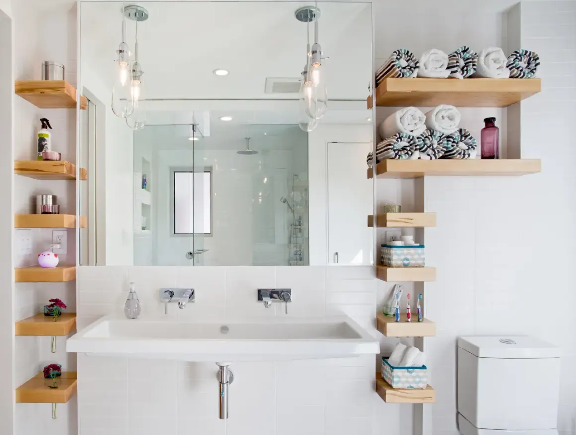 Étagères flottantes en bois pour une astuce rangement petite salle de bain. Serviettes roulées, produits de toilette et décorations y trouvent leur place.
