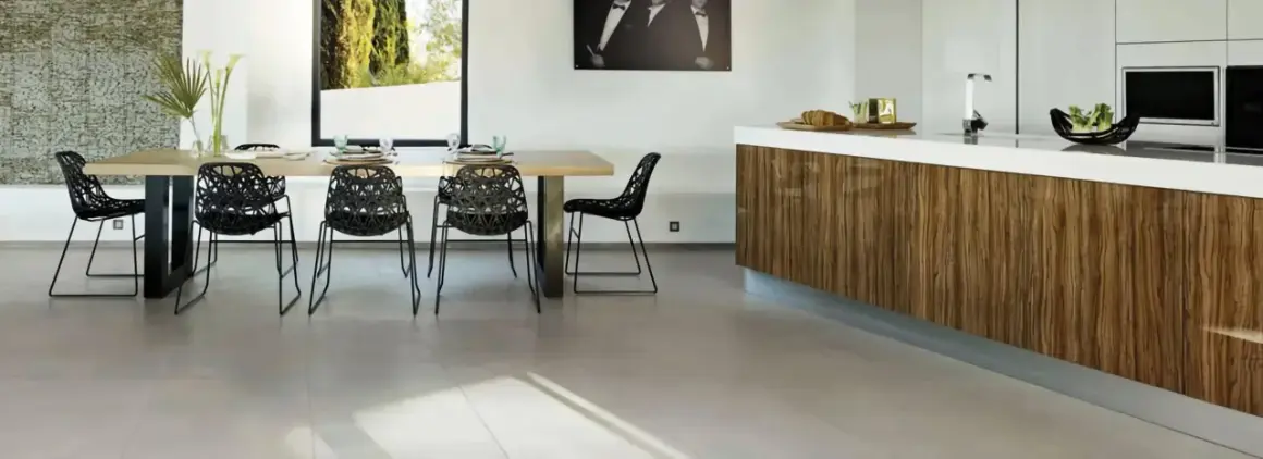 Un salon moderne avec une table en bois, des chaises noires design et un îlot de cuisine en bois. Le sol en carrelage clair complète l'ensemble.