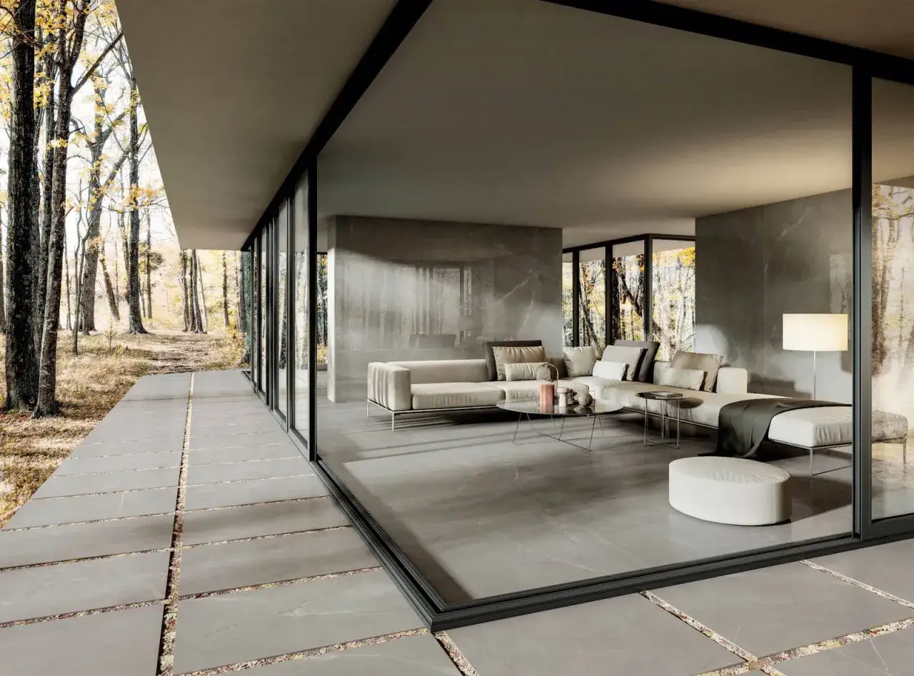Salon moderne aux murs et sols en grès cérame, avec de grandes baies vitrées donnant sur une forêt automnale.