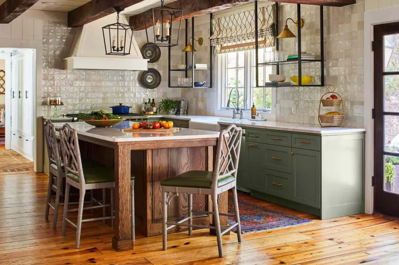 Cuisine rénovée dans un style rustique, avec un îlot central en bois, des armoires vertes et des luminaires lanternes.