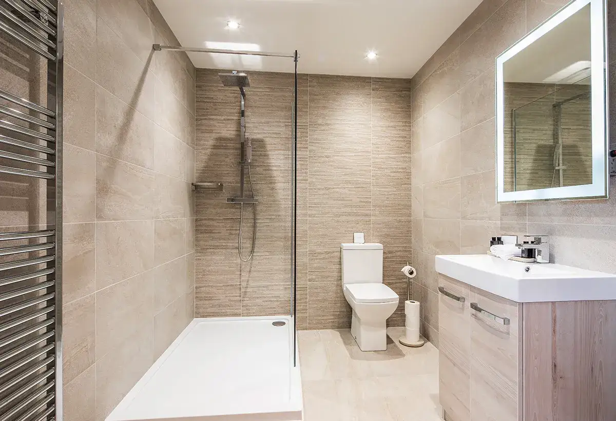 Salle de bain moderne avec douche &agrave; l'italienne, WC et lavabo. Le receveur douche semble de taille standard pour un confort optimal.