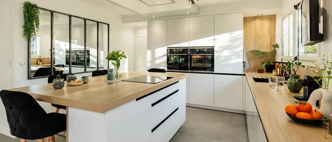 Cuisine moderne avec îlot central en bois, meubles blancs laqués et deux fours intégrés. Un modèle de cuisine simple et élégant.