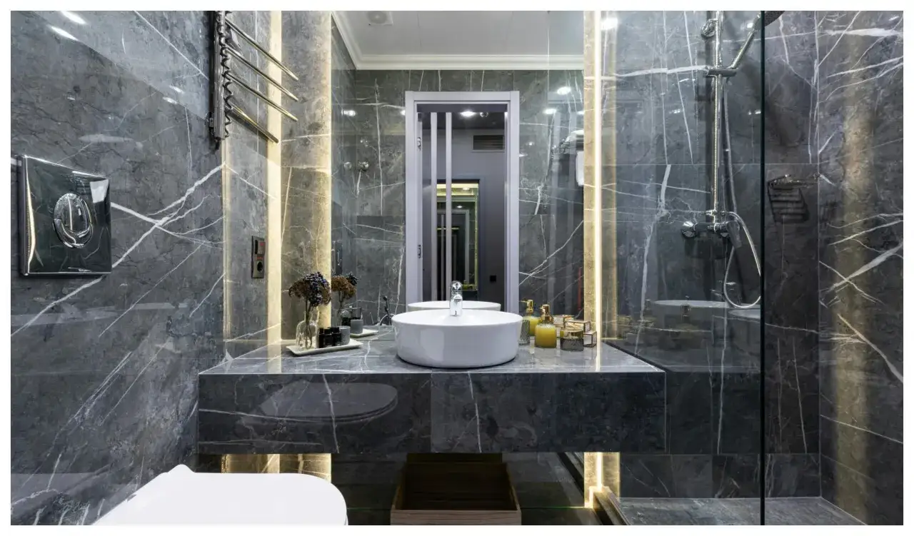 Une salle de bain de rêve aux murs de marbre gris, avec vasque ronde, douche moderne et éclairage d'ambiance.