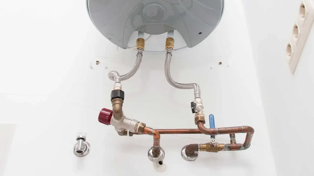 Le chauffe-eau est raccord&eacute; &agrave; un groupe de s&eacute;curit&eacute; avec des tuyaux en cuivre et des flexibles.