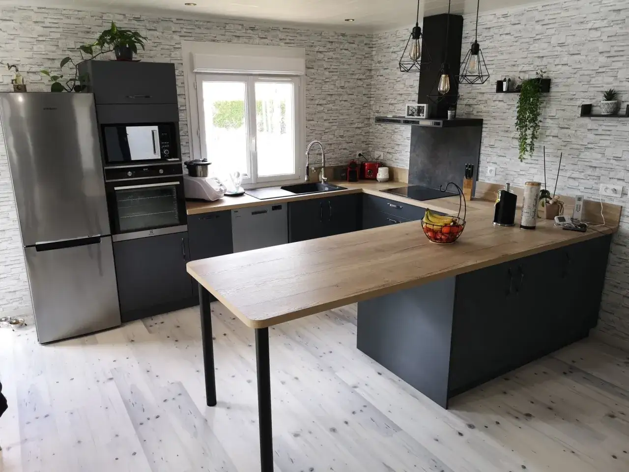 Plan d'une petite cuisine en U moderne avec îlot central en bois. Frigo, four, plaque de cuisson, évier et rangements sombres. Papier peint texturé.
