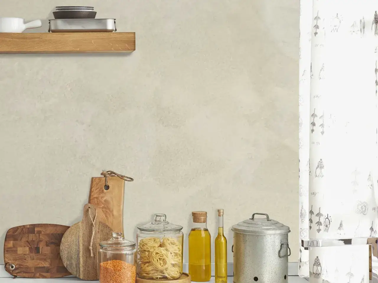 Sur un mur à la texture douce, effet taloche, des ustensiles de cuisine et des ingrédients attendent.