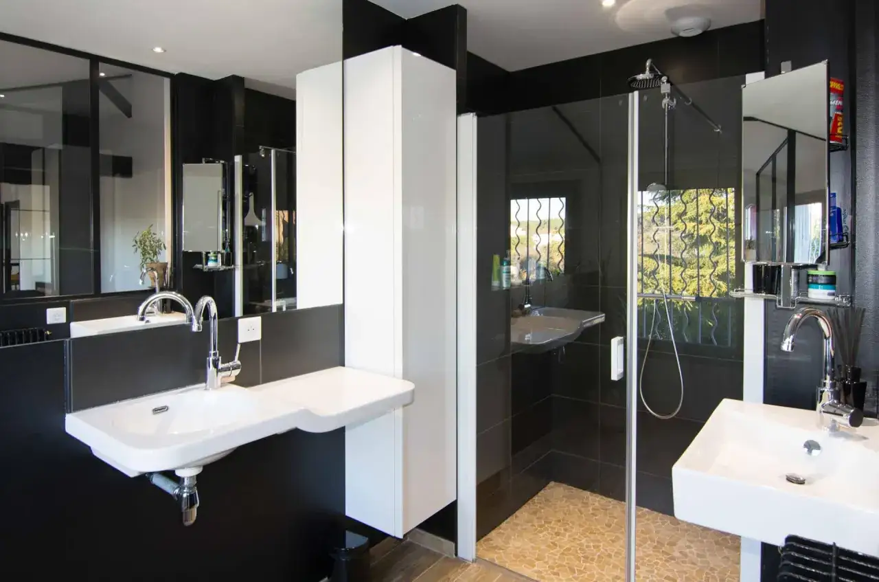 Salle de bain moderne avec double vasque, douche à l'italienne et rangements blancs. Des travaux de rénovation réussis pour un espace élégant.