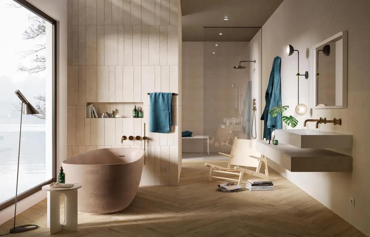 Élégante salle de bain beige et blanc avec baignoire, douche vitrée, lavabo suspendu et vue sur l'eau.