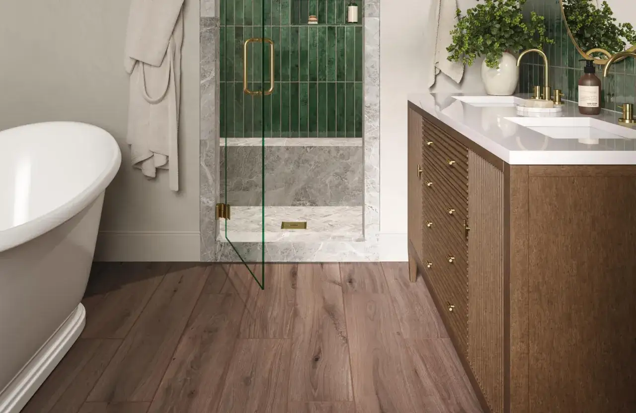 Sol de salle de bain en bois chaleureux, contrastant avec la baignoire blanche et la douche moderne aux carreaux verts.