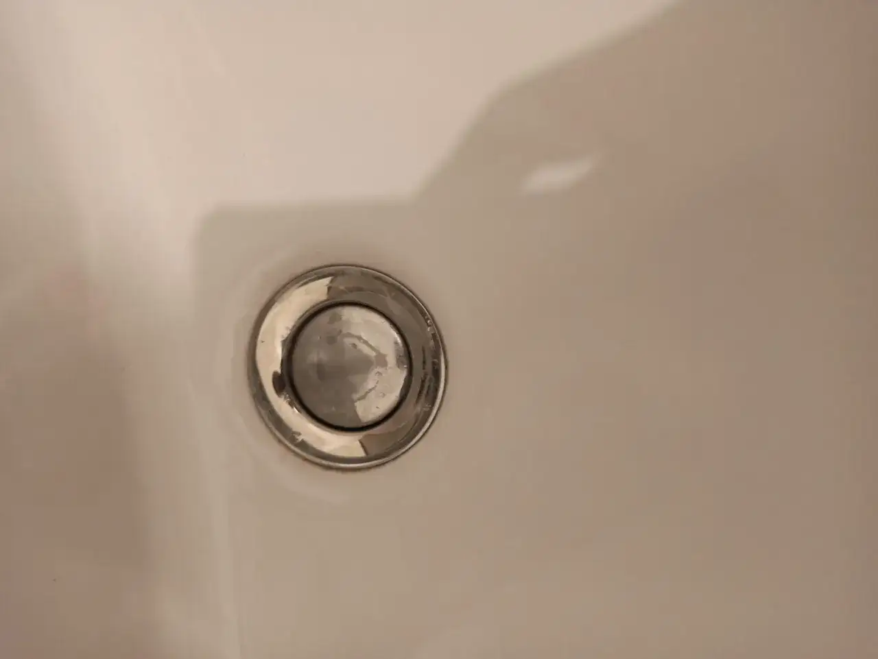 Gros plan sur un bouchon d'&eacute;vier bloqu&eacute;, avec des traces d'eau et de calcaire. L'eau ne s'&eacute;coule plus.