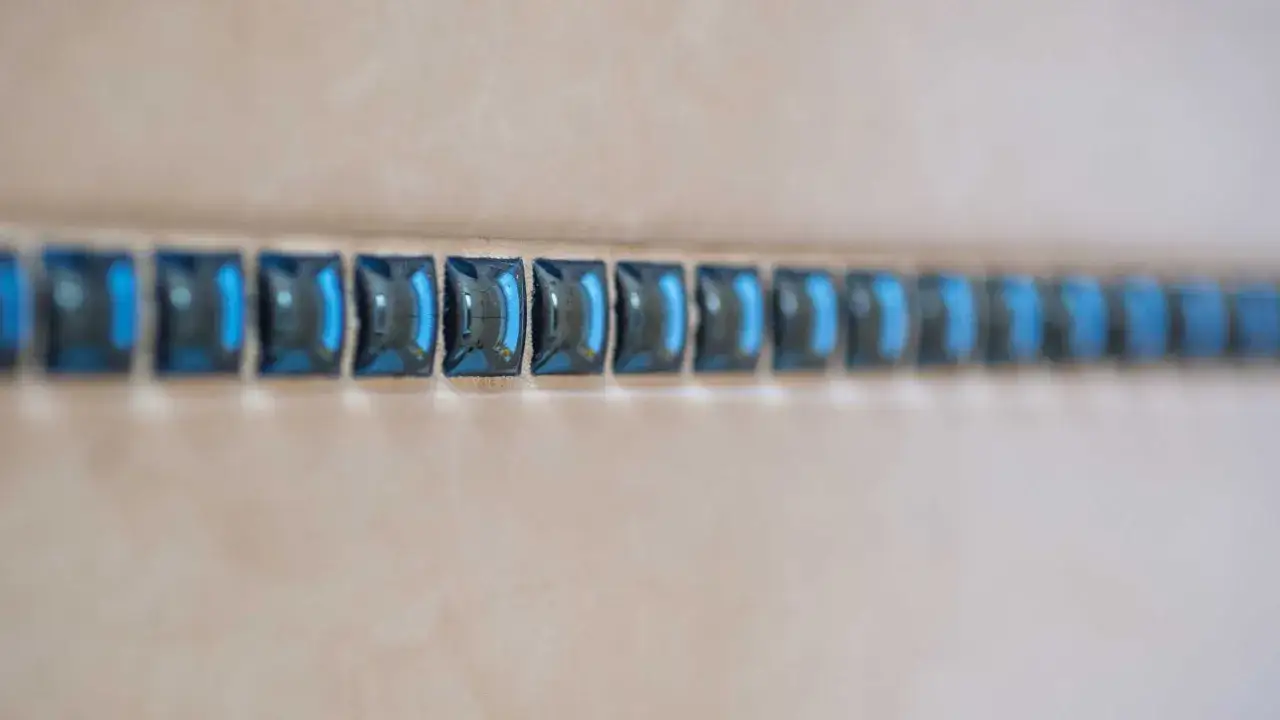Une rangée de carreaux bleus brillants forme une frise à hauteur de salle de bain, ajoutant une touche d'éclat.