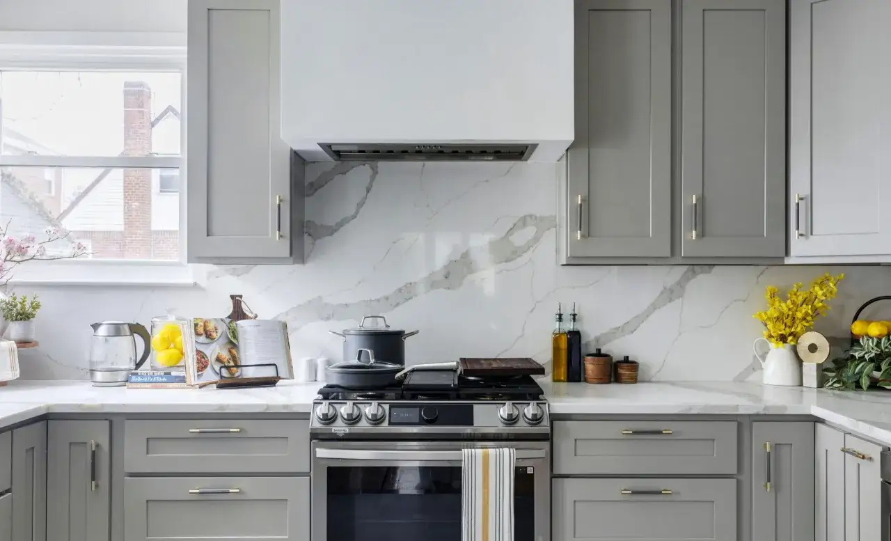 Crédence derrière plaque de cuisson gaz, avec un motif marbre blanc et gris. Des casseroles sont posées sur la plaque.