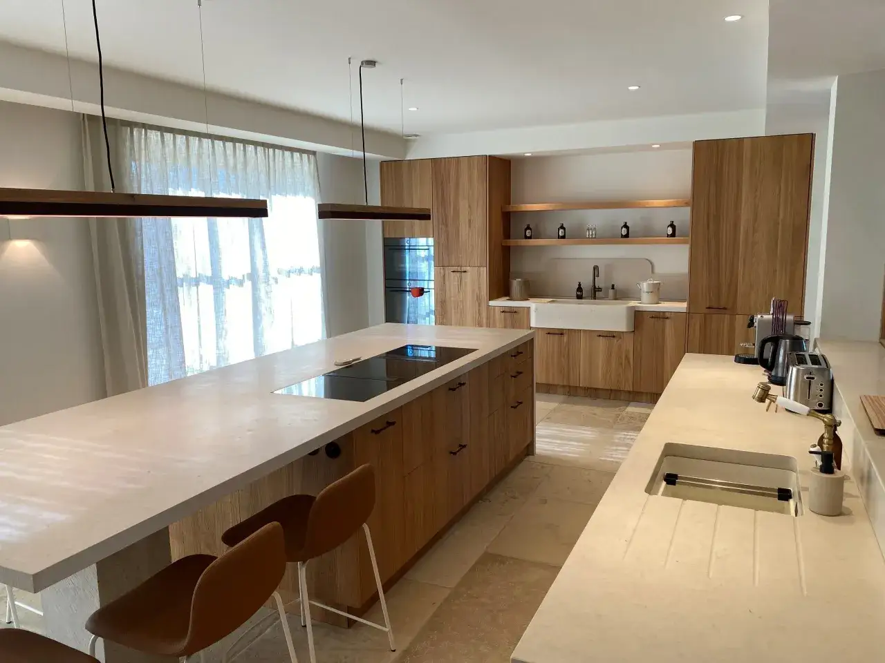 Exemple de cuisine moderne avec îlot central, plan de travail en pierre, placards en bois et éclairage suspendu.
