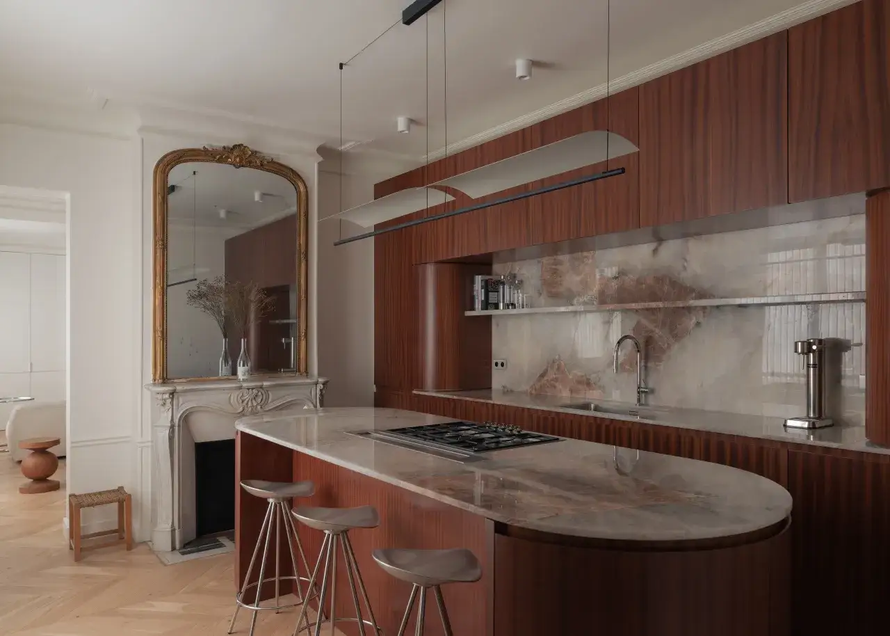 Cuisine moderne avec îlot central, plan de travail en marbre et armoires en bois. Le carrelage marron foncé des armoires crée une ambiance chaleureuse.
