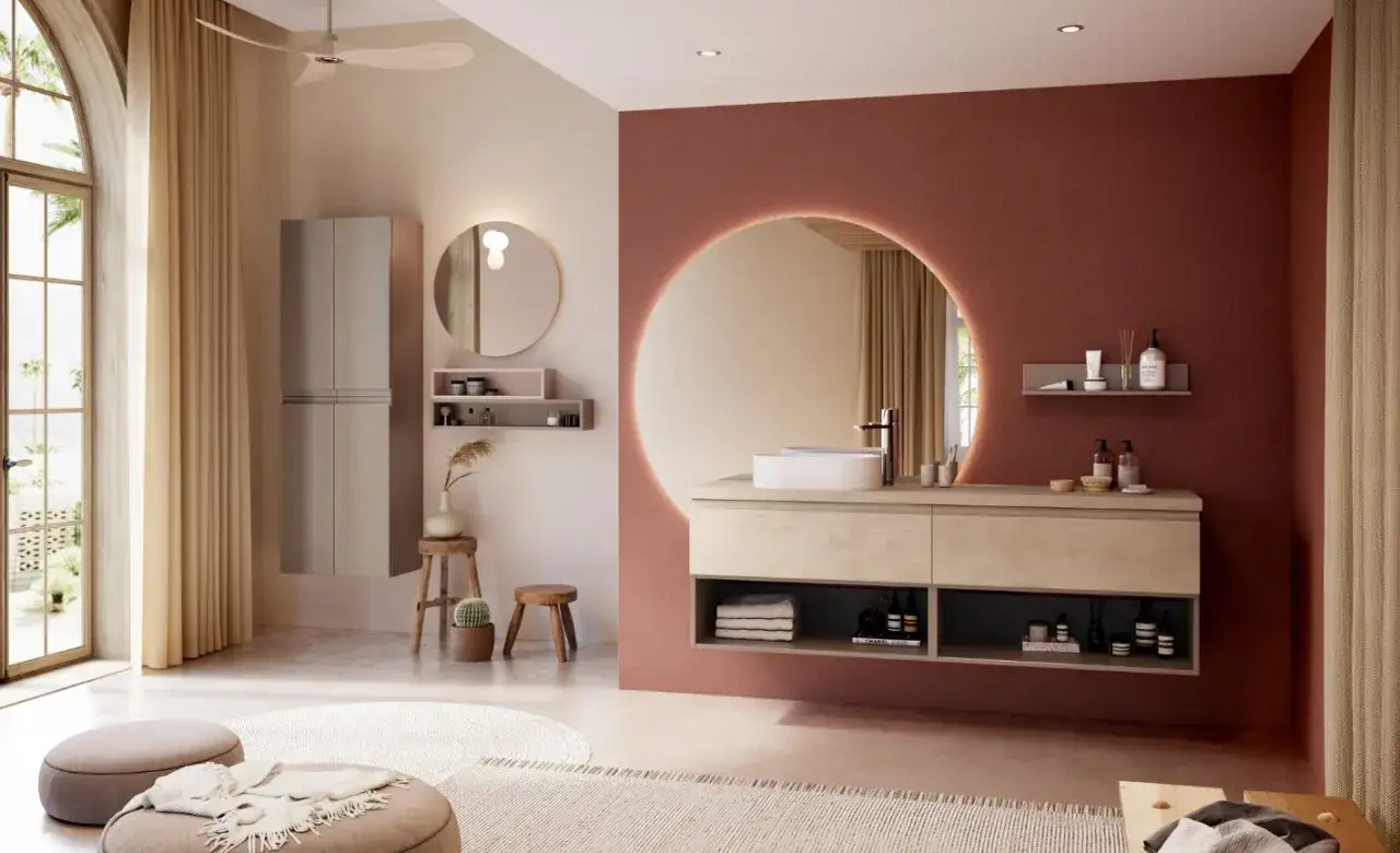 Une salle de bain moderne avec un mur d'accent couleur brique, un grand miroir circulaire rétroéclairé et un meuble vasque en bois clair.