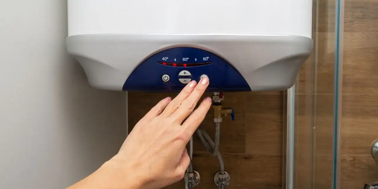 Main d'une femme ajustant la temp&eacute;rature d'un chauffe-eau &eacute;lectrique instantan&eacute;, soulignant les inconv&eacute;nients potentiels de la consommation d'&eacute;nergie.