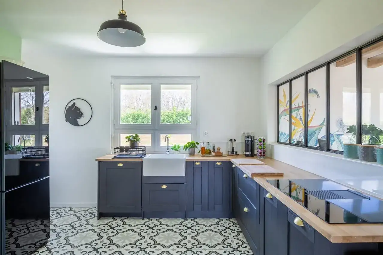Une cuisine moderne avec un sol de cuisine tendance aux motifs géométriques, des armoires bleu marine et un évier blanc.