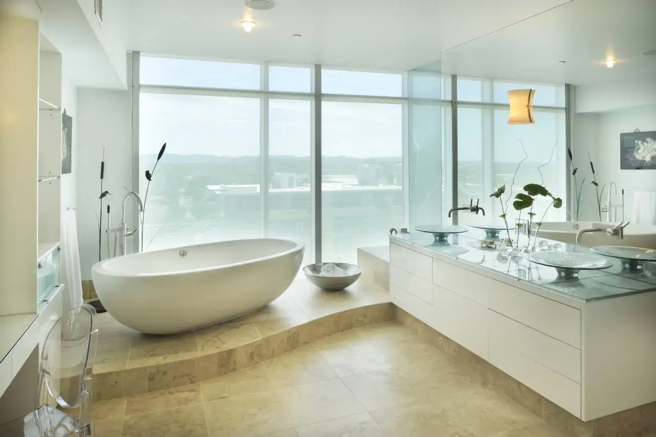 Salle de bain moderne avec baignoire &icirc;lot sur&eacute;lev&eacute;e sur une marche, double vasque et grande fen&ecirc;tre panoramique.