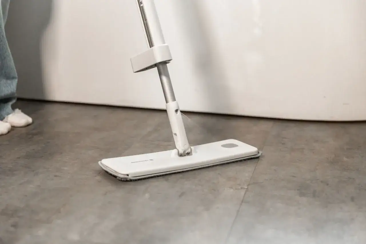 Un balai plat pulvérise de l'eau pour un nettoyage efficace du carrelage.