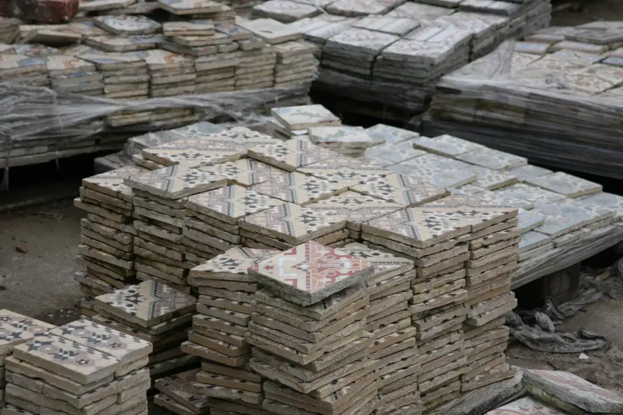 Piles de carreaux anciens aux motifs géométriques colorés, prêts pour le recyclage.