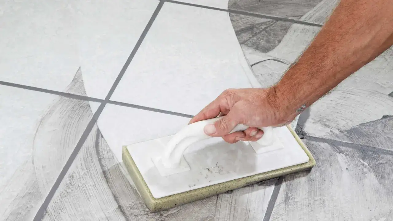 Main tenant, quand nettoyer carrelage après joint, utilise une éponge pour enlever l'excédent de mortier.