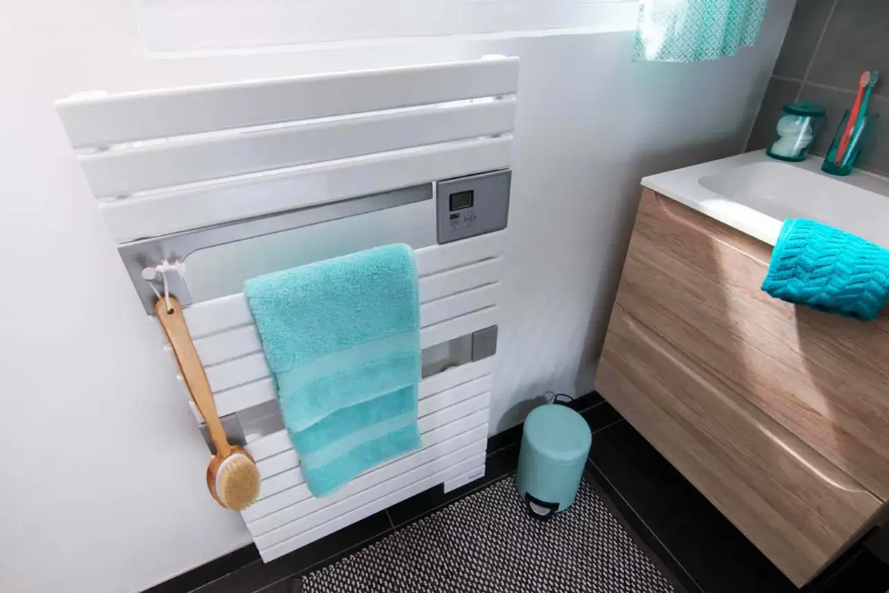 Un s&egrave;che-serviettes blanc moderne, avec une serviette turquoise et une brosse de bain. La hauteur du s&egrave;che-serviette est id&eacute;ale pour une salle de bain.