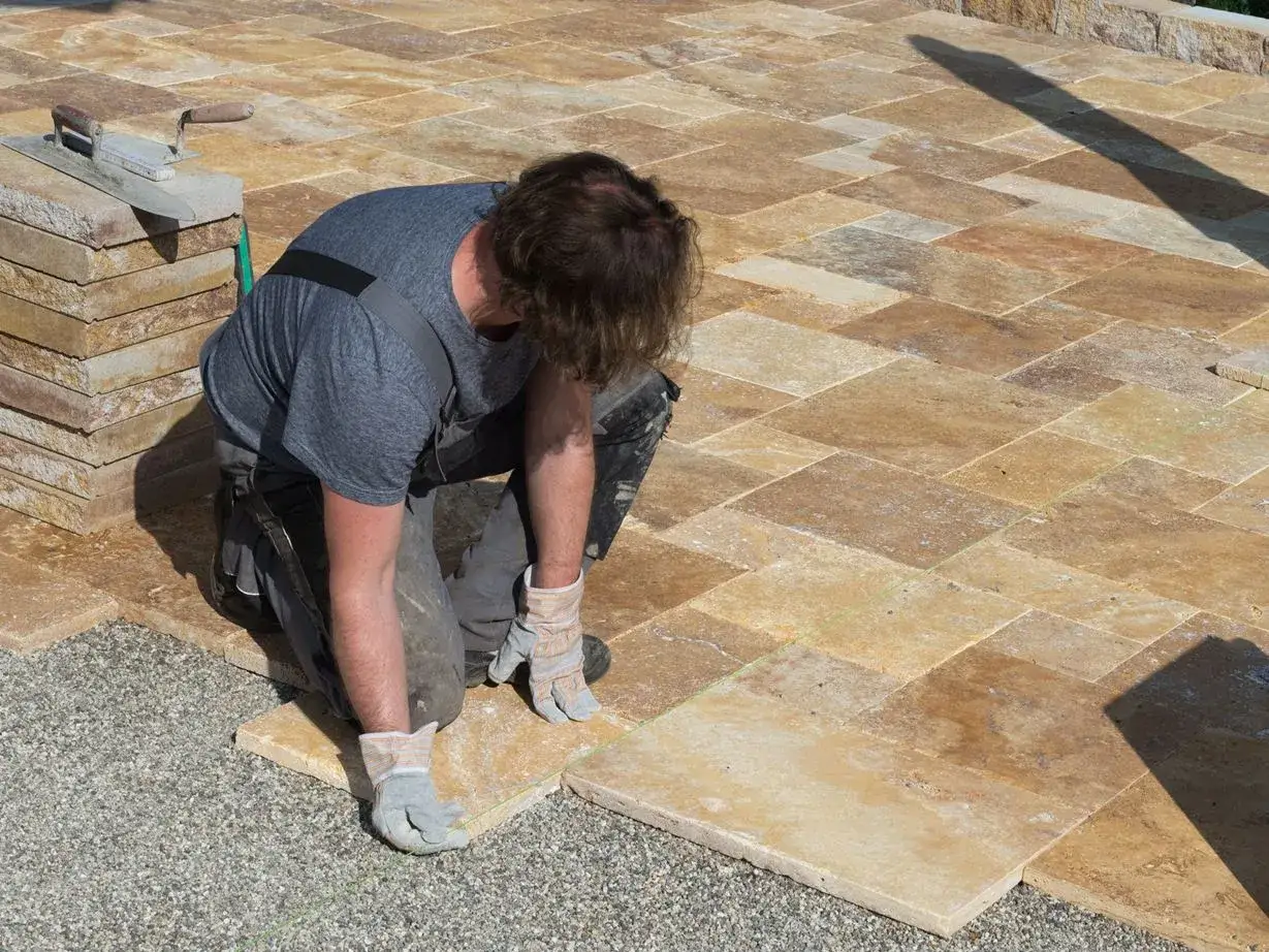 Un ouvrier pose des dalles de travertin pour créer une terrasse.