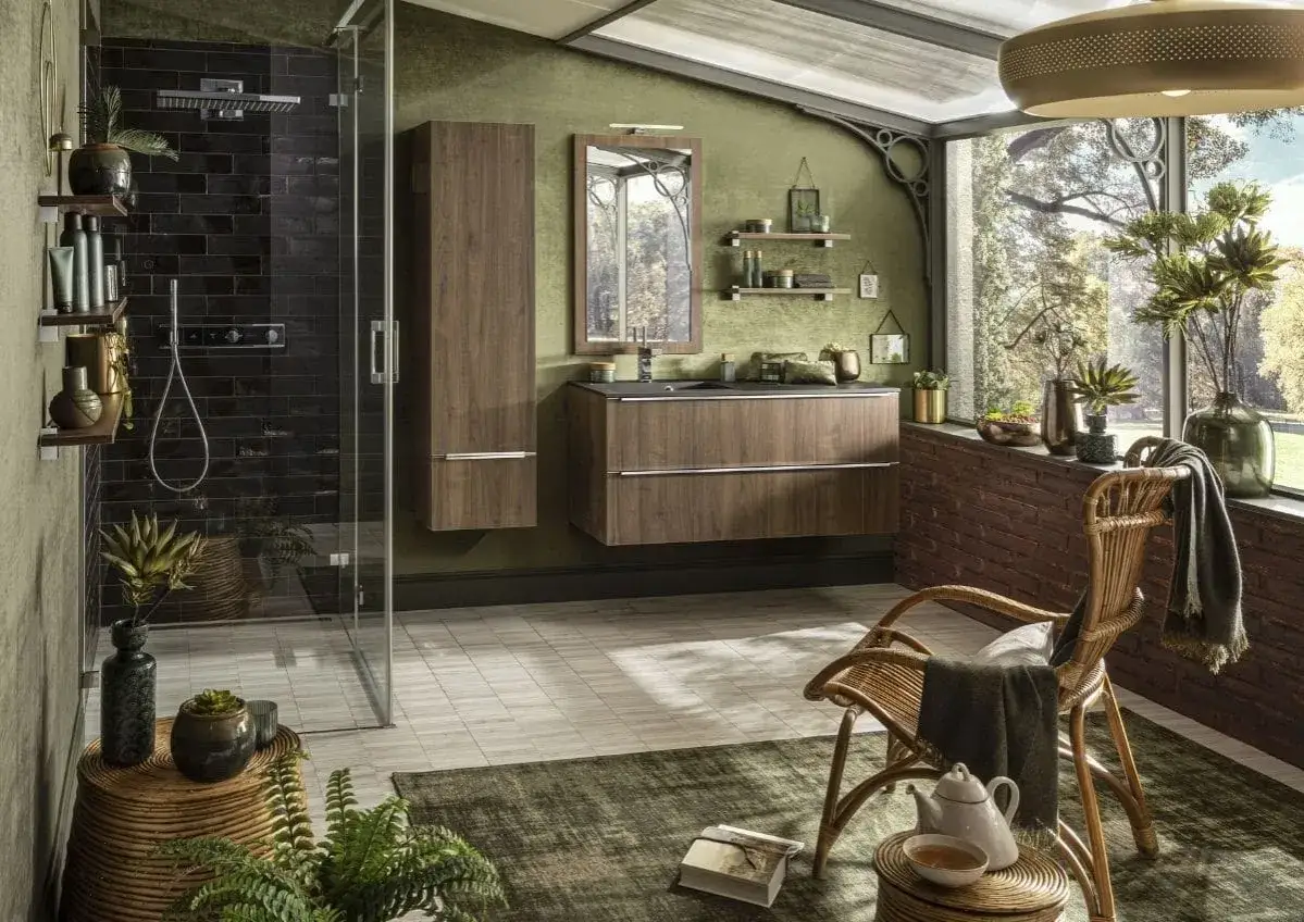 Une salle de bain verte avec une douche moderne, des meubles en bois, un fauteuil en rotin et une vue sur la nature.