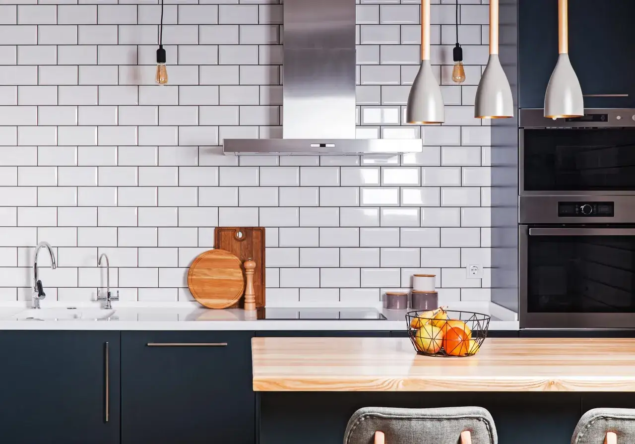 Cuisine moderne avec pose carrelage mural métro blanc, plan de travail en bois, hotte inox et électroménagers intégrés.