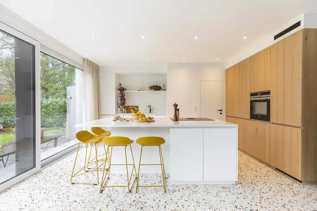 Cuisine moderne avec îlot blanc, tabourets jaunes vifs et armoires en bois. Parfaites idées cuisine pour un espace lumineux et accueillant.